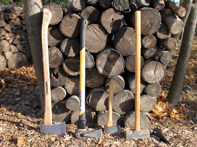 tools for chopping wood leaning against a stack of wood